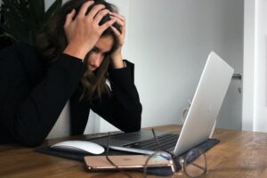 Femme se prenant la tête à deux mains devant son ordinateur