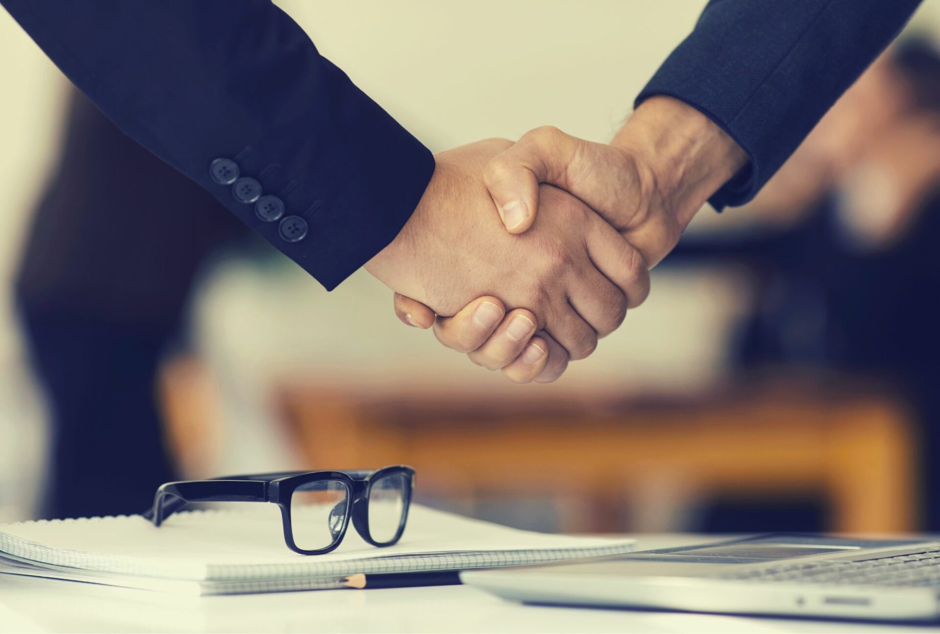 Poignée de main entre professionnels avec lunettes sur le bureau